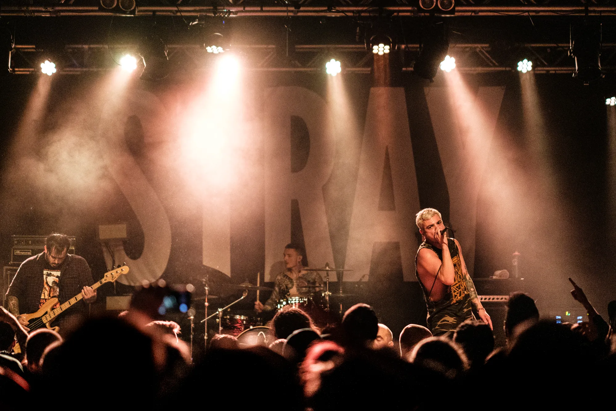 Band performing on stage with a large illuminated STRAY sign behind them