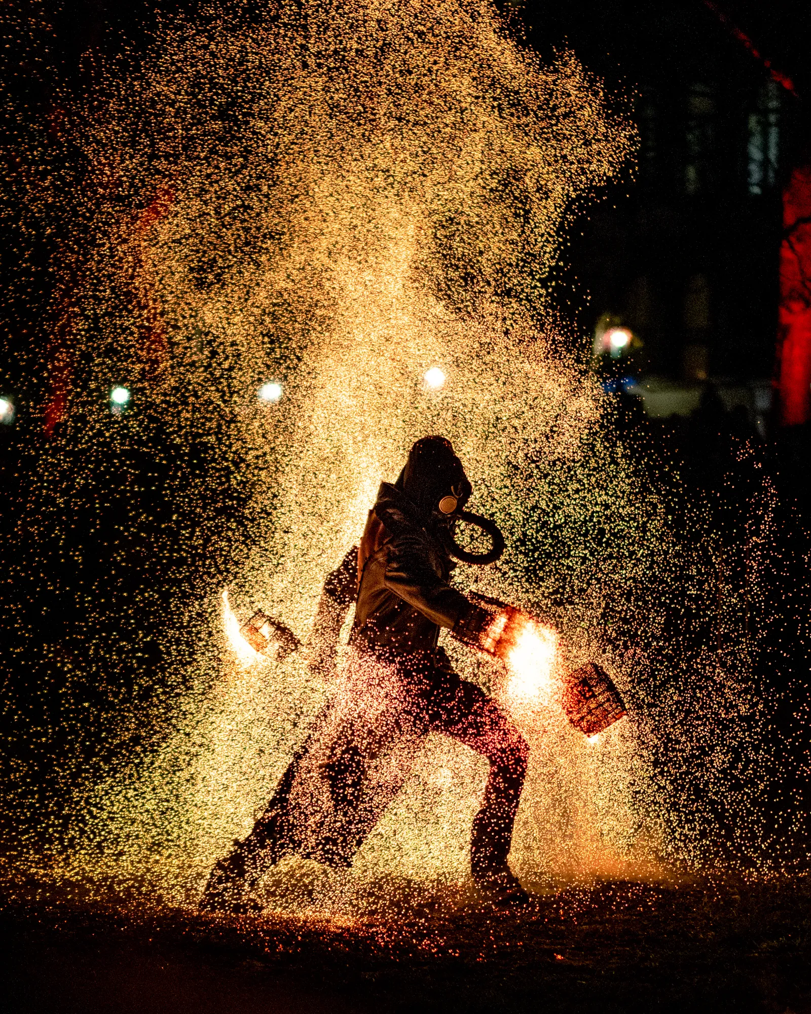 Fire performer surrounded by a cascading shower of sparks in the dark