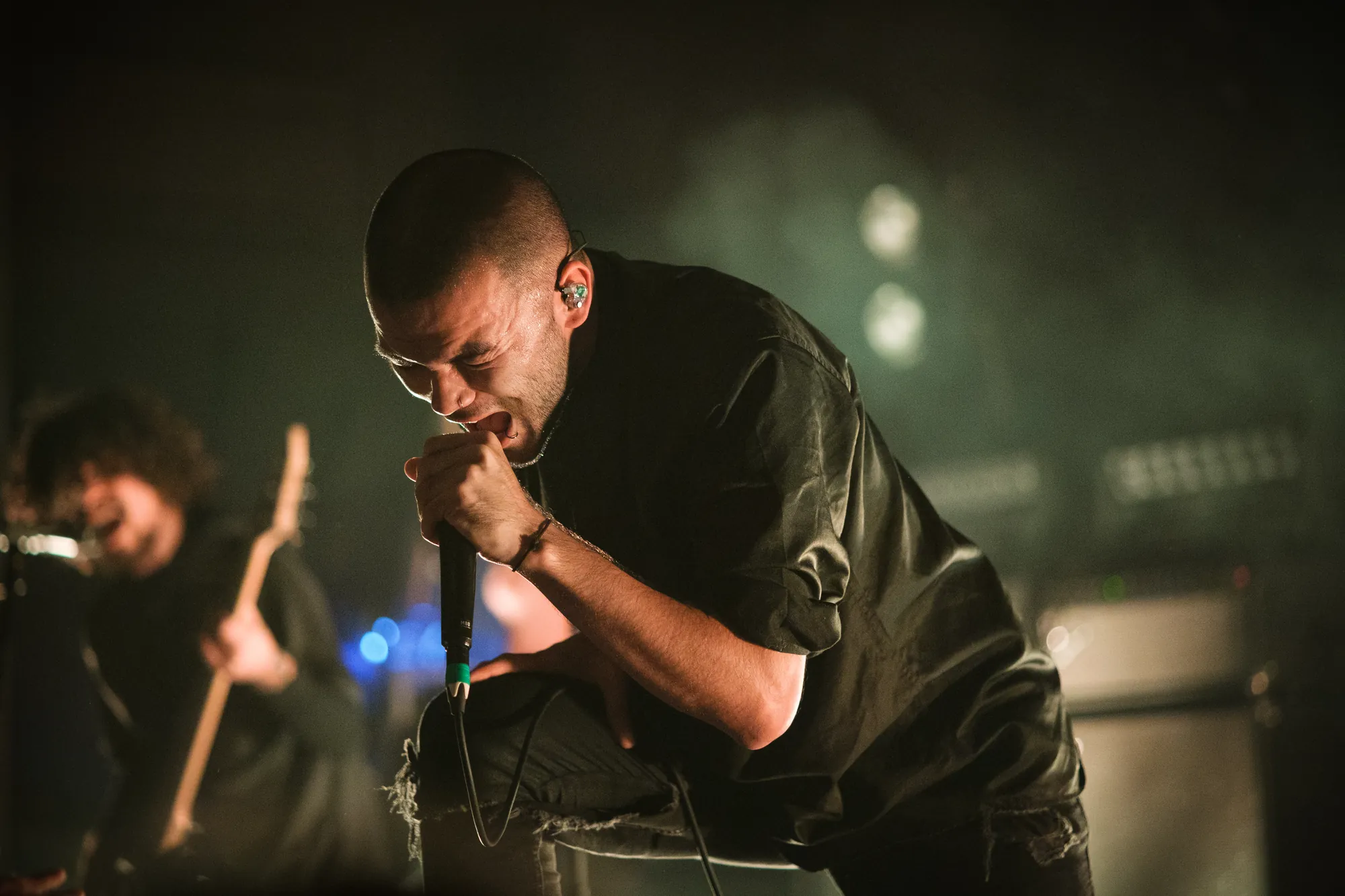 Singer gripping the microphone with both hands on a dark smoky stage