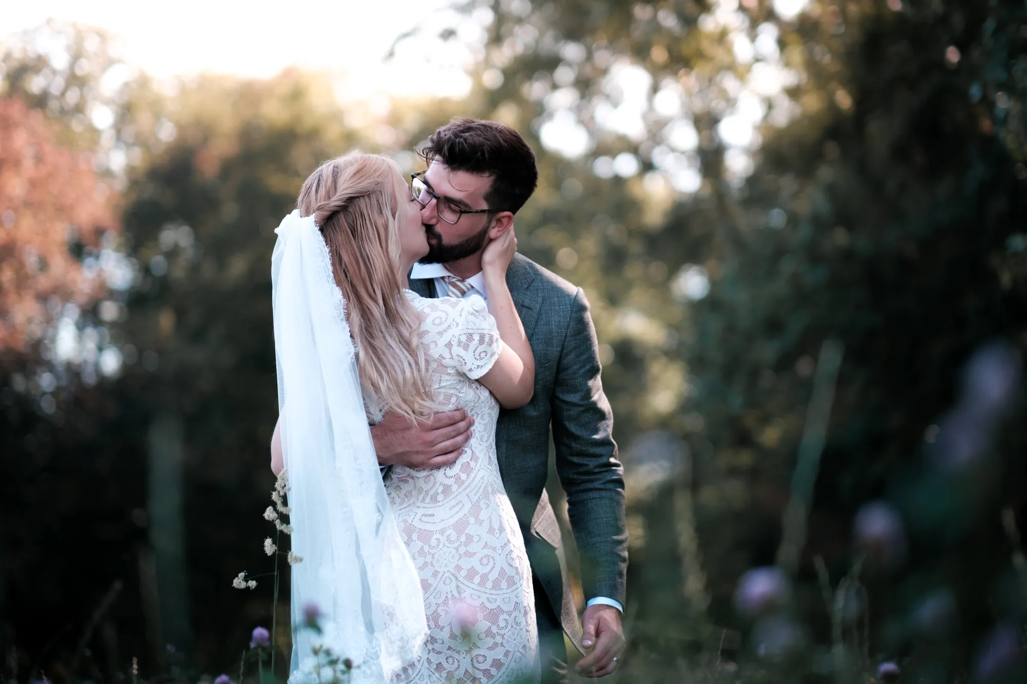 Bride and groom kissing in a wildflower meadow at golden hour